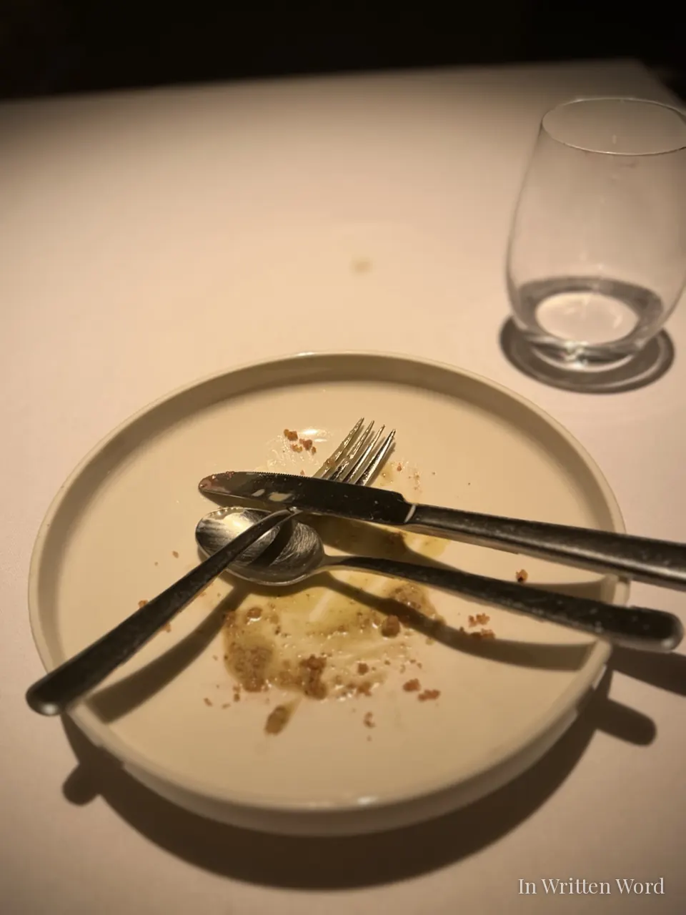 An empty white plate with a fork, knife, and spoon crossed at the center at Aheste restaurant in Istanbul, signaling the satisfying end of a long meal