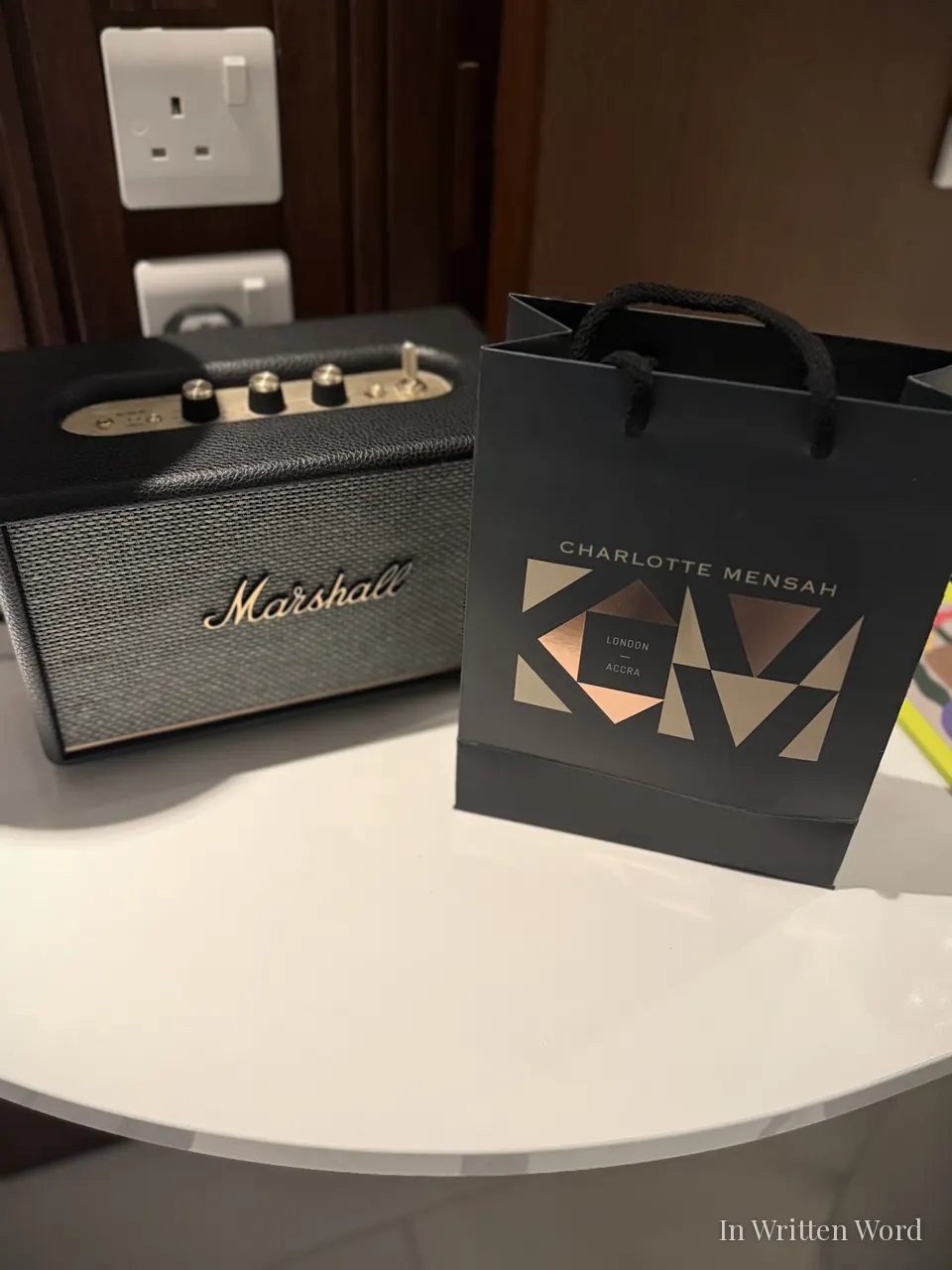 Charlotte Mensah London haircare bag placed beside a speaker, reflecting a personal salon visit experience.