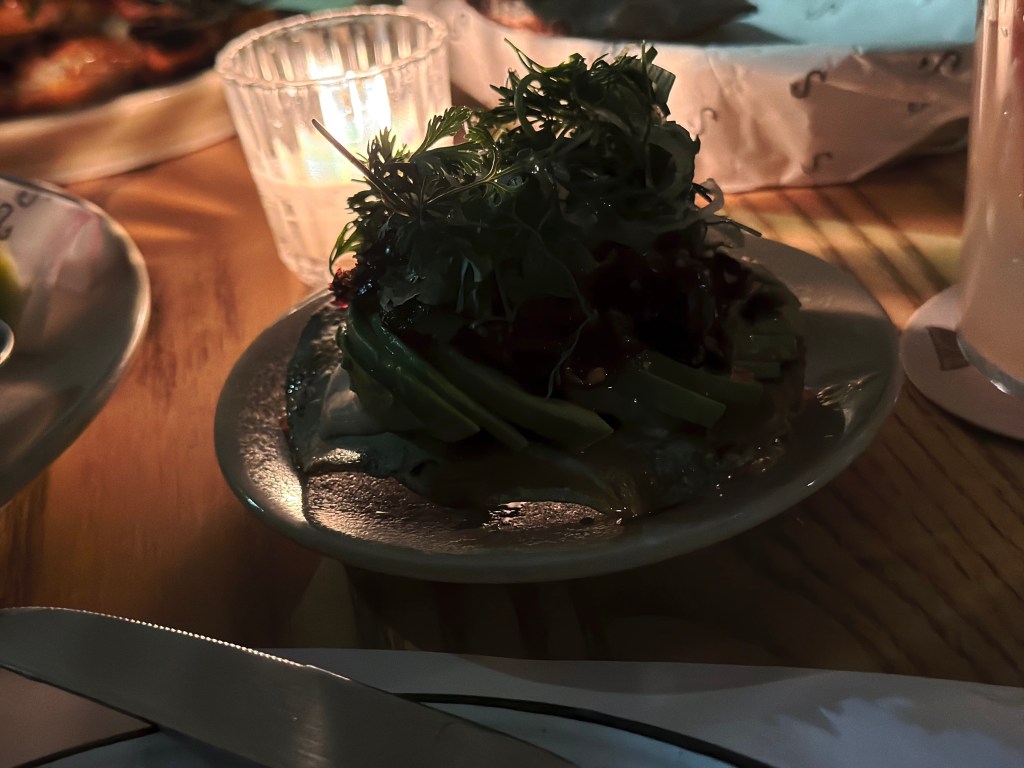 Avocado tostada at Campobaja in Mexico City topped with fresh herbs and crispy elements.